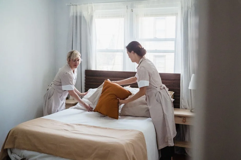 A woman carefully wraps a sofa in protective material while packing boxes in a bright room.